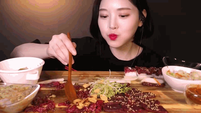 a woman is sitting at a table eating a large amount of food