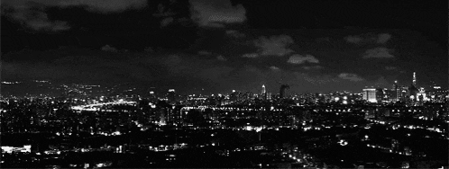 a black and white photo of a city at night with lots of lights