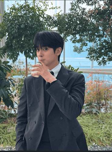 a man in a suit holds a cup of coffee in his hand