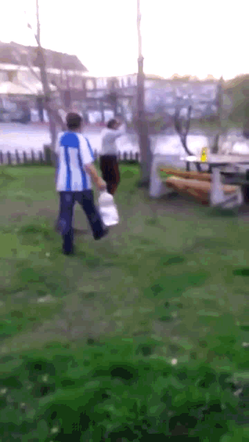 a man in a blue and white shirt is holding a bottle of water