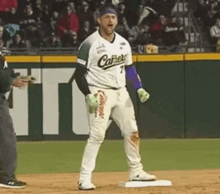 a baseball player is standing on a base while a referee looks on .