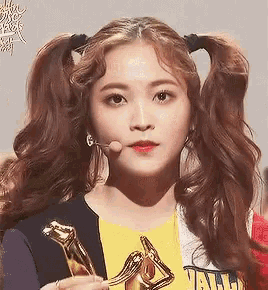 a woman with pigtails is holding a gold trophy in her hand .