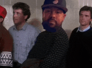 a group of men are standing in a room and one of them is wearing a hat that says washington redskins