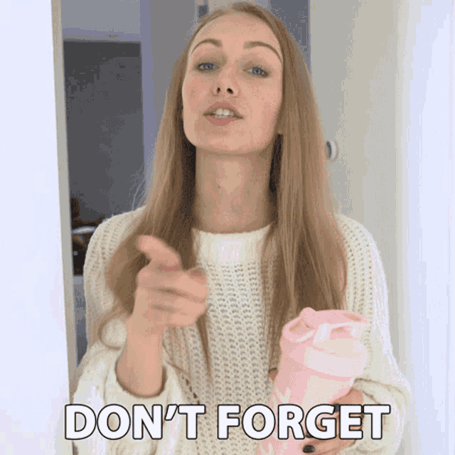 a woman in a white sweater holds a pink shaker and points at the camera with the words " don 't forget " below her