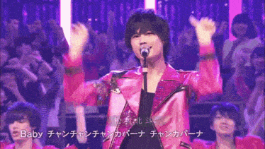 a man in a pink jacket singing into a microphone with the word baby on the bottom