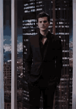 a man in a suit is standing in front of a window