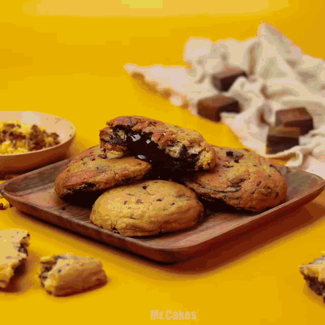 a wooden tray filled with chocolate chip cookies with the words mr.cakes below them