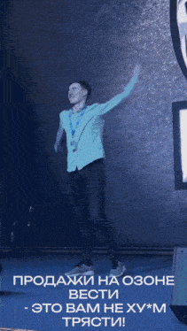 a man in a blue shirt is dancing in front of a sign that says ozone вести