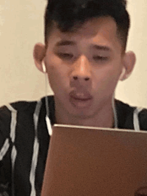 a man wearing ear buds looks at a laptop screen