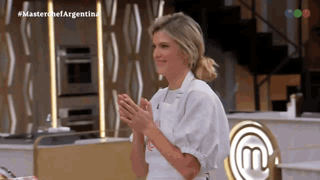 a woman applauds in front of a sign that says master chef argentina