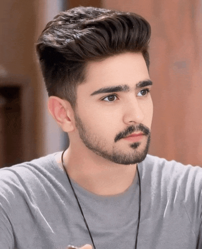a young man with a beard is wearing a grey t-shirt