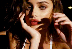 a close up of a woman 's face with her hands on her chin