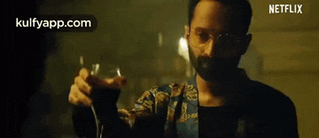 a man with a beard and headphones is holding a glass of wine .