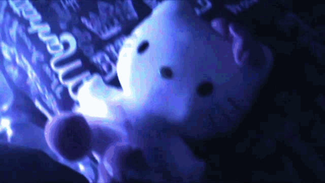 a stuffed hello kitty is laying on a bed with a bottle of coca cola in the background