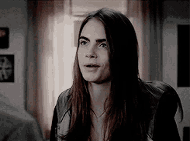 a woman with long hair is sitting in front of a window in a room .