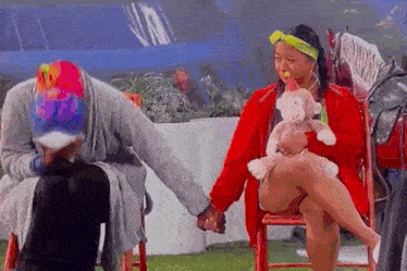 a man and a woman are sitting in chairs holding hands and a woman is holding a stuffed monkey .