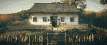 a white thatched house with a wooden fence around it