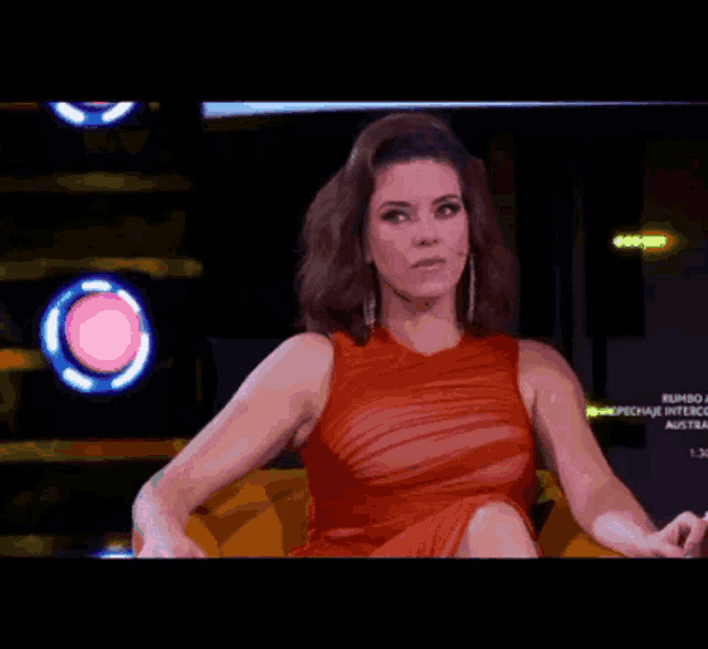 a woman in a red dress is sitting in front of a sign that says rumbo