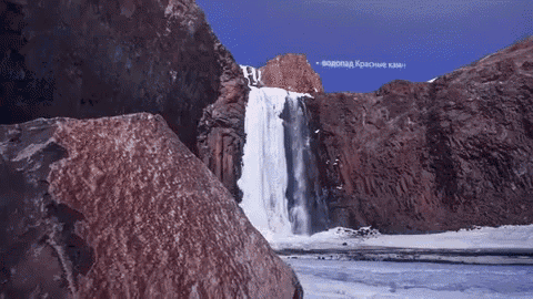 a waterfall is surrounded by rocks and ice with a sign in the sky that says " водопад красные камни "