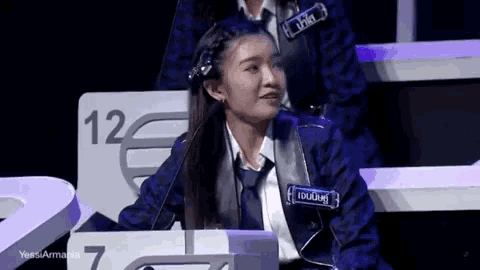 a woman in a suit and tie is sitting in front of a microphone in a room .