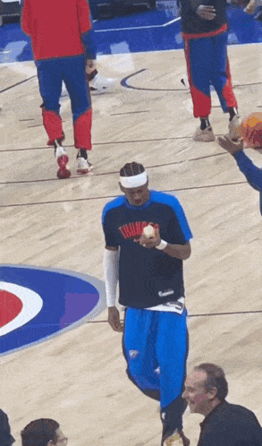 a man wearing a shirt that says thunder holds a ball