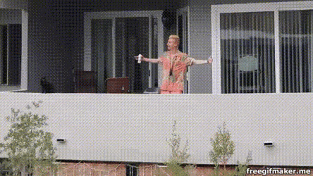 a man standing on a balcony with his arms outstretched and a freegifmaker.me watermark