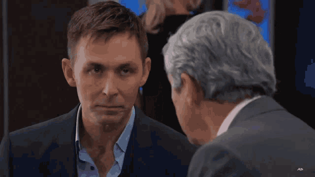a man in a suit talks to another man in a suit