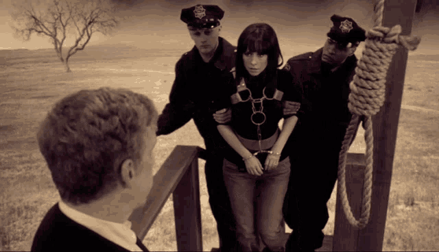 a woman in handcuffs is being led by police officers to a gallows