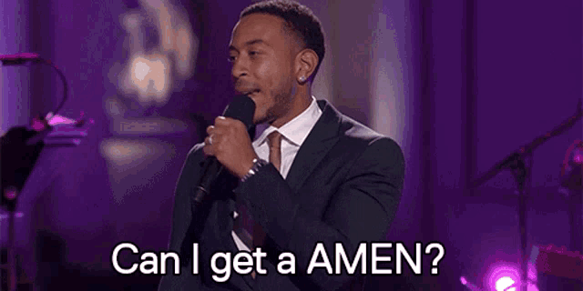 a man in a suit and tie singing into a microphone with the words can i get a amen written below him