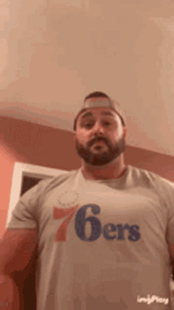 a man with a beard wearing a 76ers shirt
