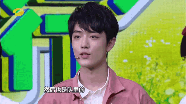 a man wearing a pink jacket stands in front of a green background