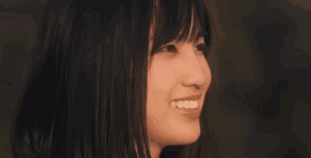 a close up of a woman 's face smiling and looking to the side .