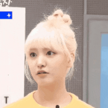a woman with blonde hair is wearing a yellow shirt and making a face .