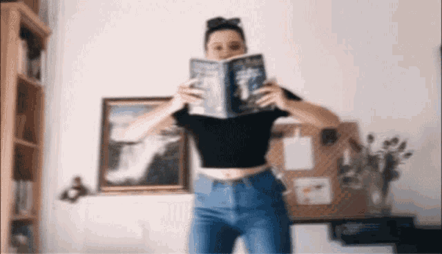 a woman is reading a book in front of a picture of a waterfall