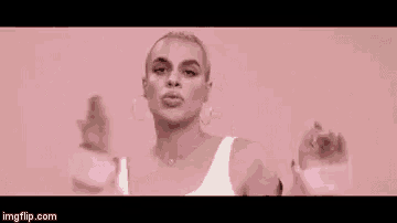 a woman in a white dress is standing in front of a pink background .