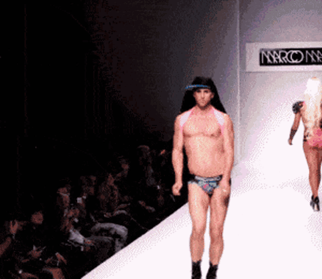 a man and a woman are walking down a runway in front of a sign that says narcone