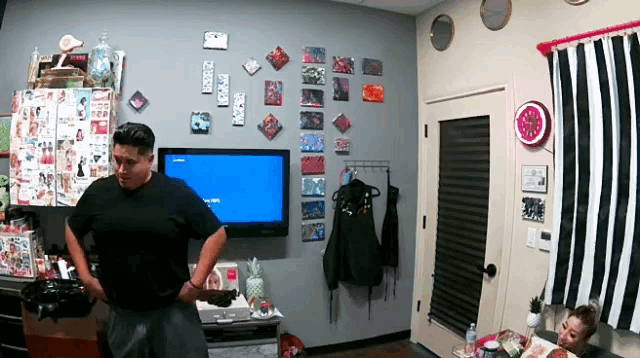 a man in a black shirt stands in front of a television that says ' nintendo ' on the screen