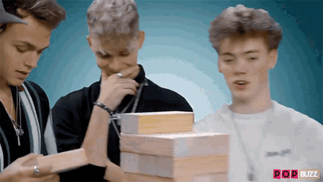a group of young men are playing a game of jenga with pop buzz written in the corner
