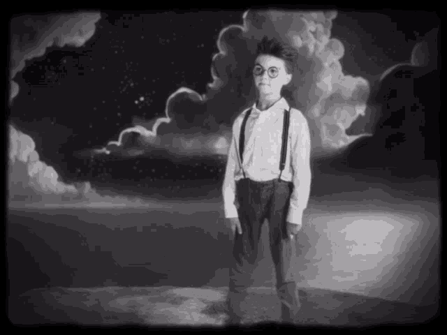 a black and white photo of a boy wearing suspenders