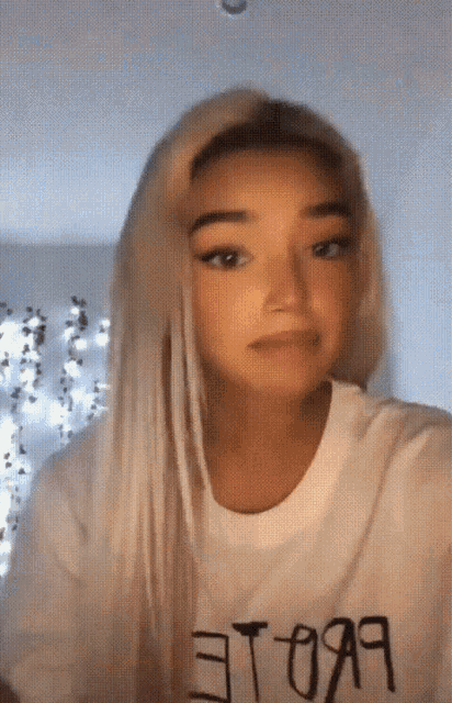 a girl with blonde hair is wearing a white t-shirt that says " et-099 " on it