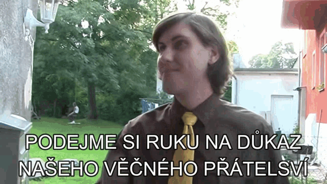 a man in a brown shirt and yellow tie stands in front of a sign that says podejme si ruko na dukaz