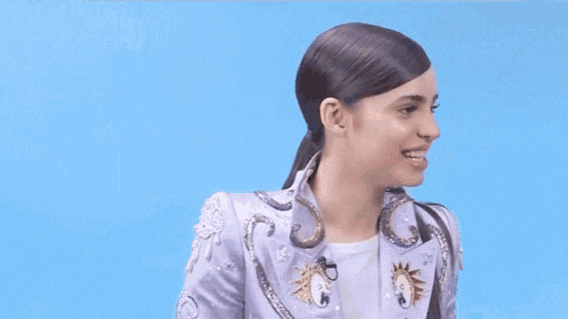 a woman in a purple jacket is making a face with her hands