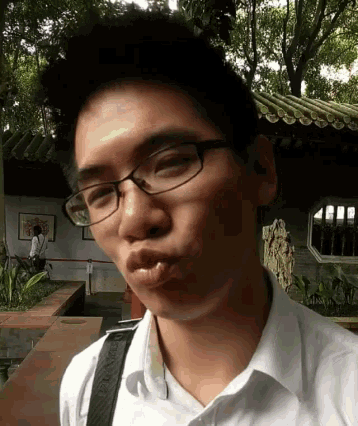 a young man wearing glasses and a white shirt with a green strap around his neck