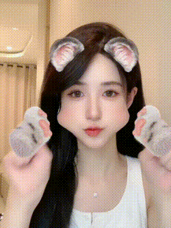 a woman with cat ears on her head is holding a cat paw in her hand .