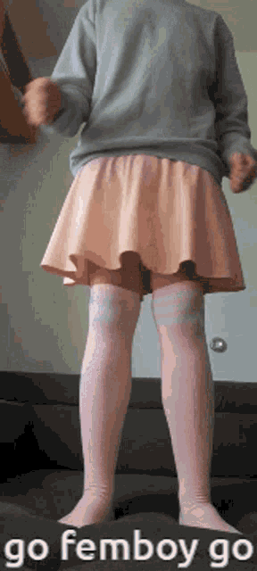 a person wearing a pink skirt and knee high socks is standing on a couch with the caption " go femboy go "