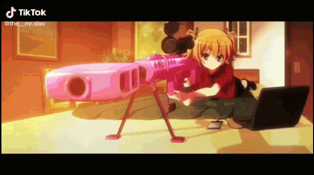 a girl is holding a pink sniper rifle next to a laptop .