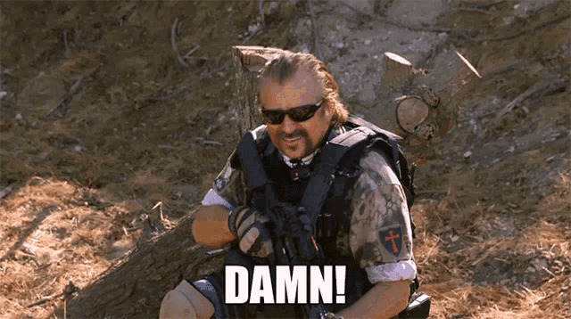 a man with a beard and sunglasses is holding a gun and the word damn is above him