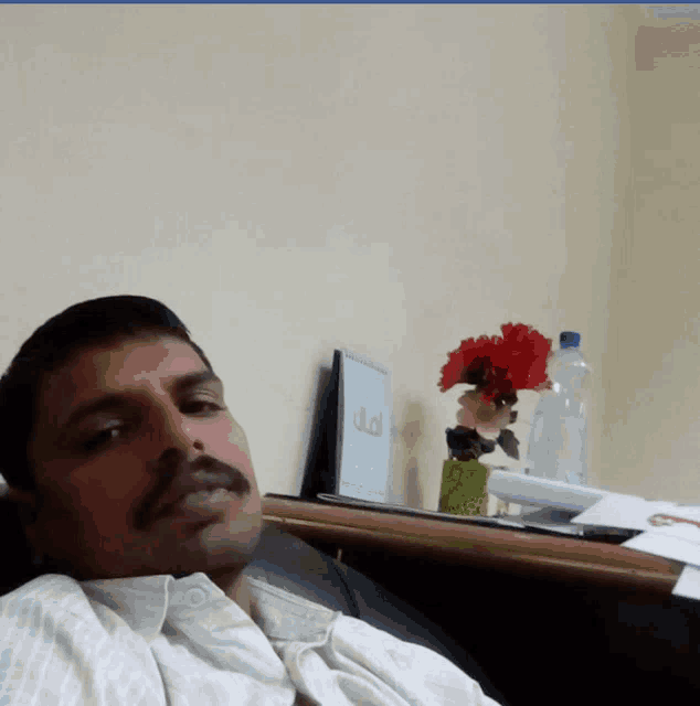a man sits in front of a table with flowers and a sign that says ' tp ' on it
