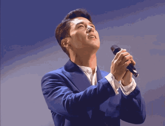 a man in a blue suit holds a microphone in his hands