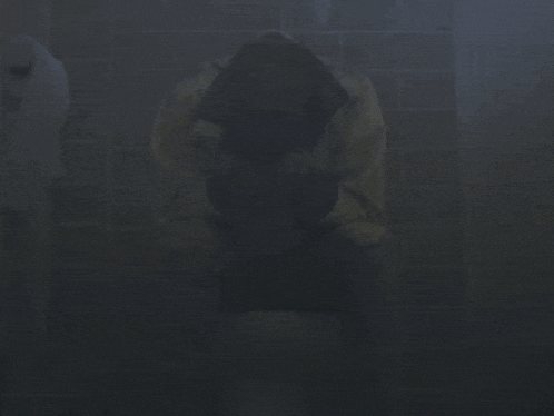 a person in a yellow jacket is sitting on a toilet in the dark
